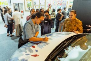 Arief Witjaksana, Seniman Instalasi Visual, menandatangani karya seni The Mallacan Leisure pada DENZA D9. (Foto: Dok DENZA)